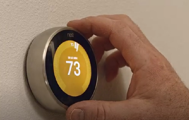 a hand adjusting a smart thermostat